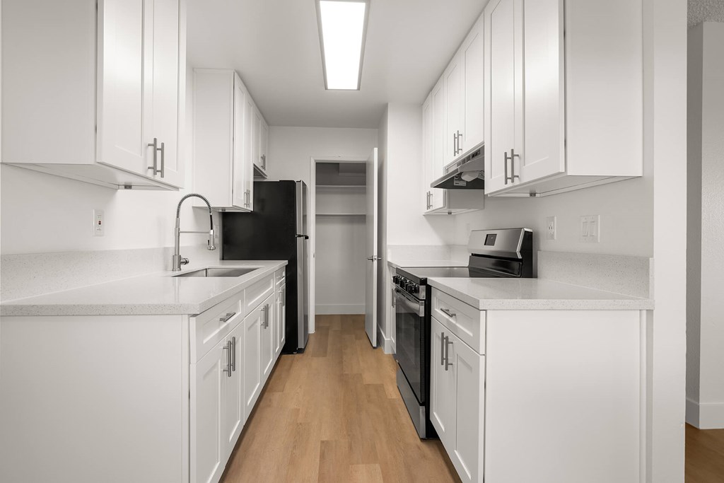 A kitchen with white cabinets and black appliances.