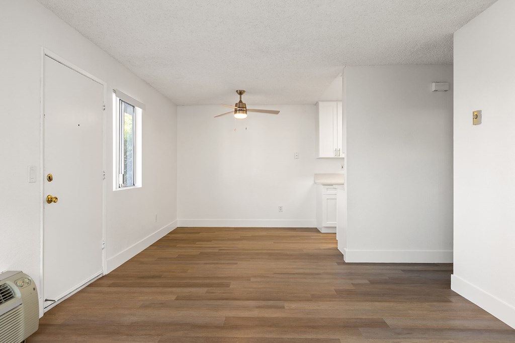 A room with a ceiling fan and wooden flooring.