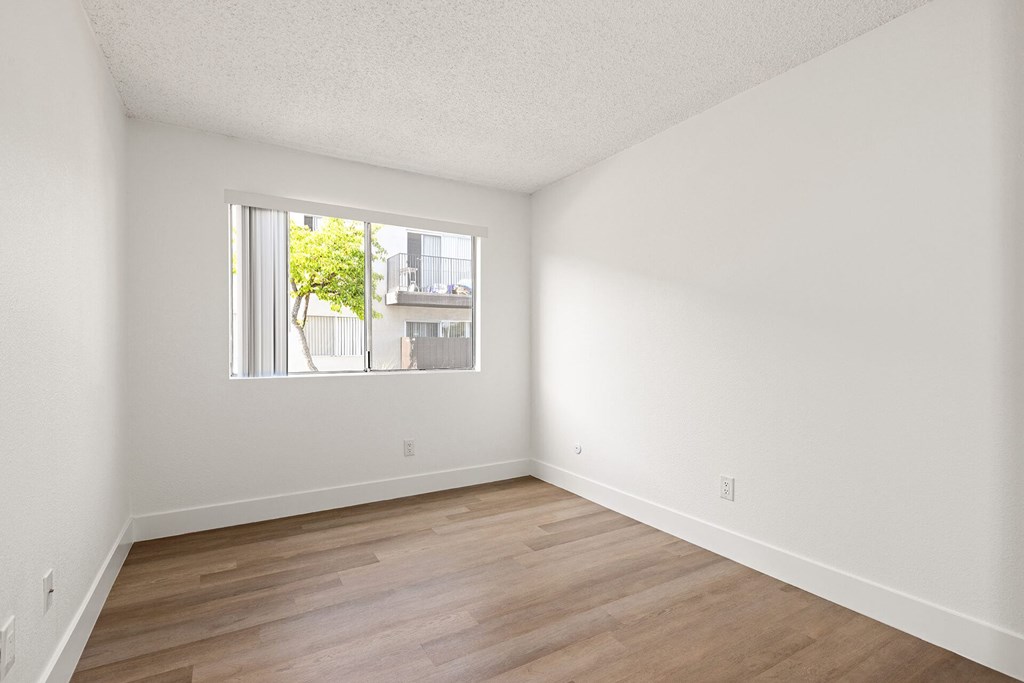 Empty room with a window and wooden flooring.