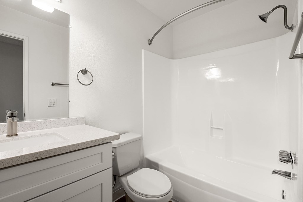 A white bathroom with a toilet, sink, and bathtub.
