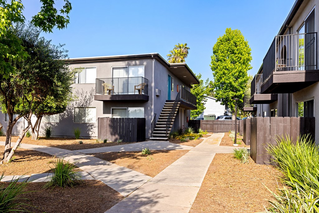 A modern apartment complex with a well-maintained garden and pathway.