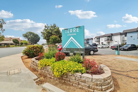 A sign for Terre at Bentonia stands in front of a flower bed.