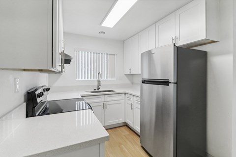 A modern kitchen with a stainless steel refrigerator and white cabinets.