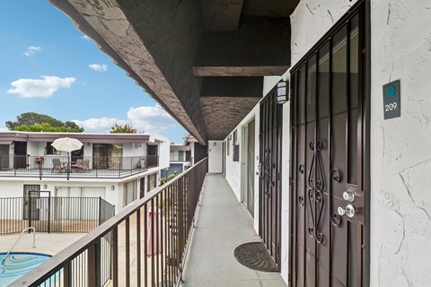 A balcony with a pool and a building in the background.