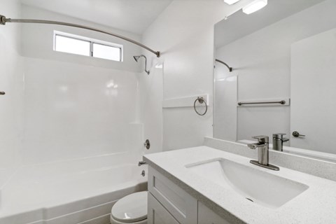 A white bathroom with a toilet, sink, and mirror.
