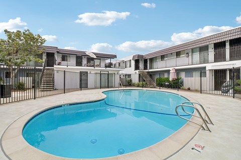 A swimming pool in front of a building with a black fence around it.