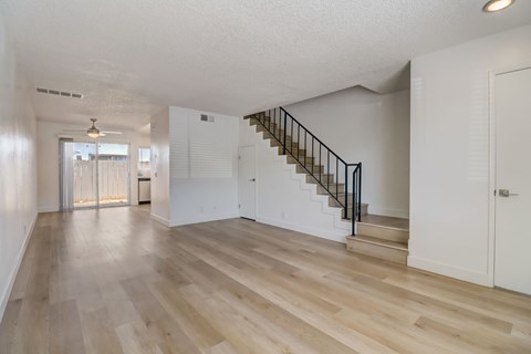 A spacious room with wooden floors and a staircase.