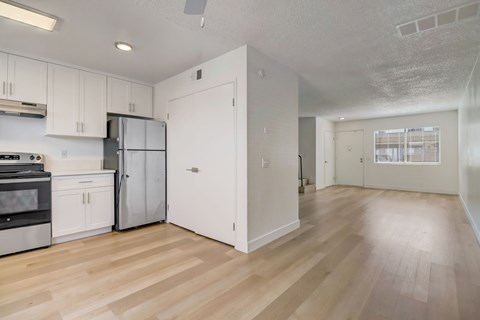 A kitchen with white cabinets and a wooden floor.