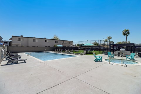 A pool area with a hot tub and lounge chairs.