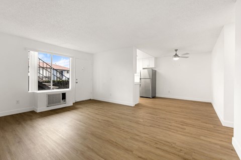 A room with wooden flooring and a window showing a view of a building.