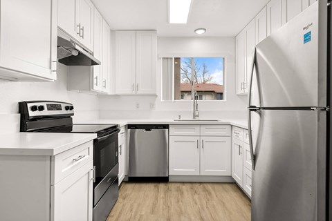 A modern kitchen with white cabinets and stainless steel appliances.