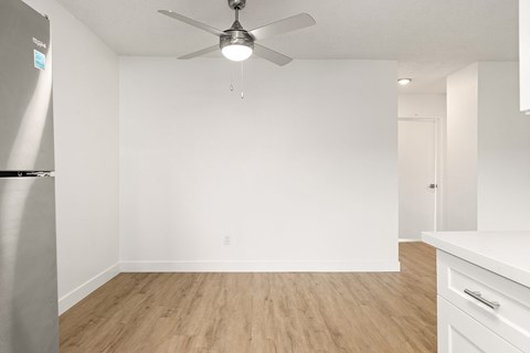 A room with a ceiling fan and a refrigerator.