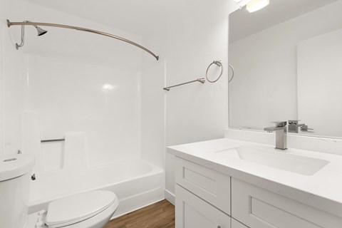 A white bathroom with a toilet, sink, and shower.