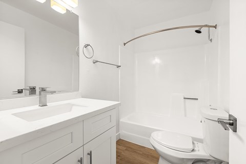 A white bathroom with a toilet, sink, and shower.