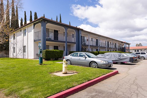 A silver car is parked in front of a building with a yellow fire hydrant.