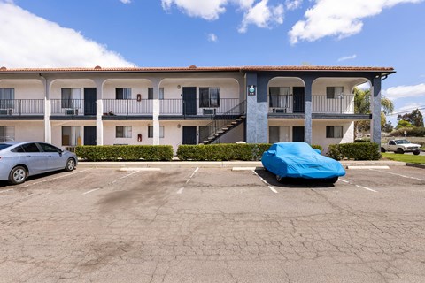 A car is parked in a parking lot in front of a building.