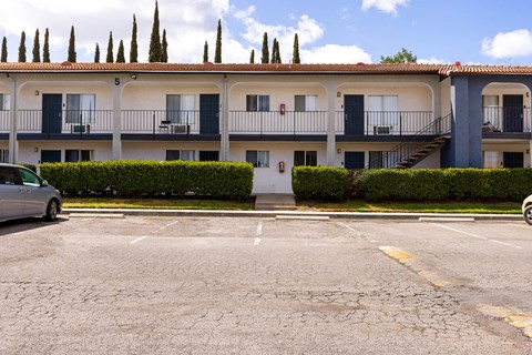 A parking lot in front of a building with a car parked.