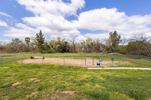 A baseball field with a green sign and a blue trash can.