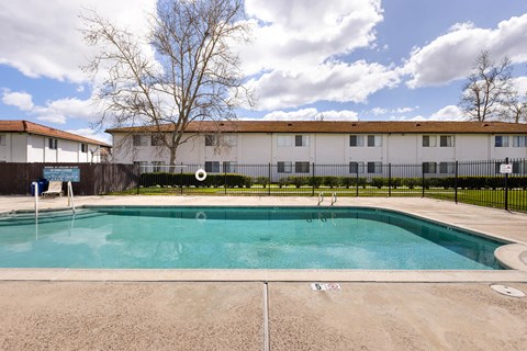 A swimming pool in front of a building with a fence around it.