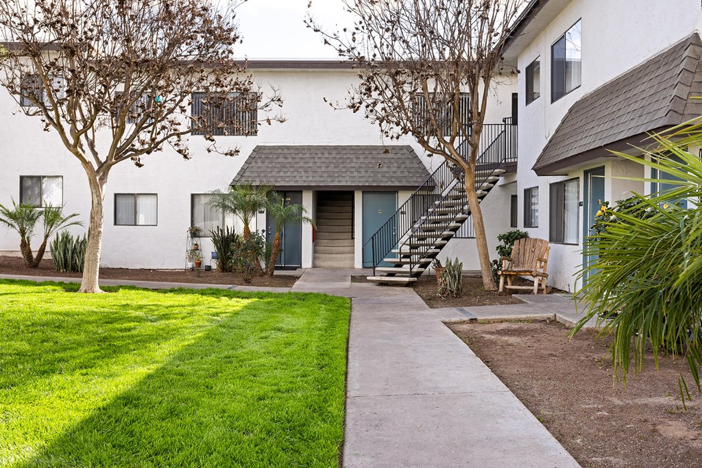 A white house with a grey roof and a green lawn.