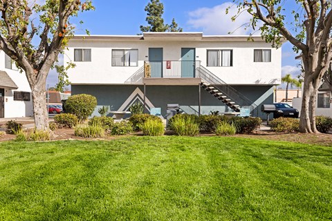 A white two-story house with a green lawn in front.