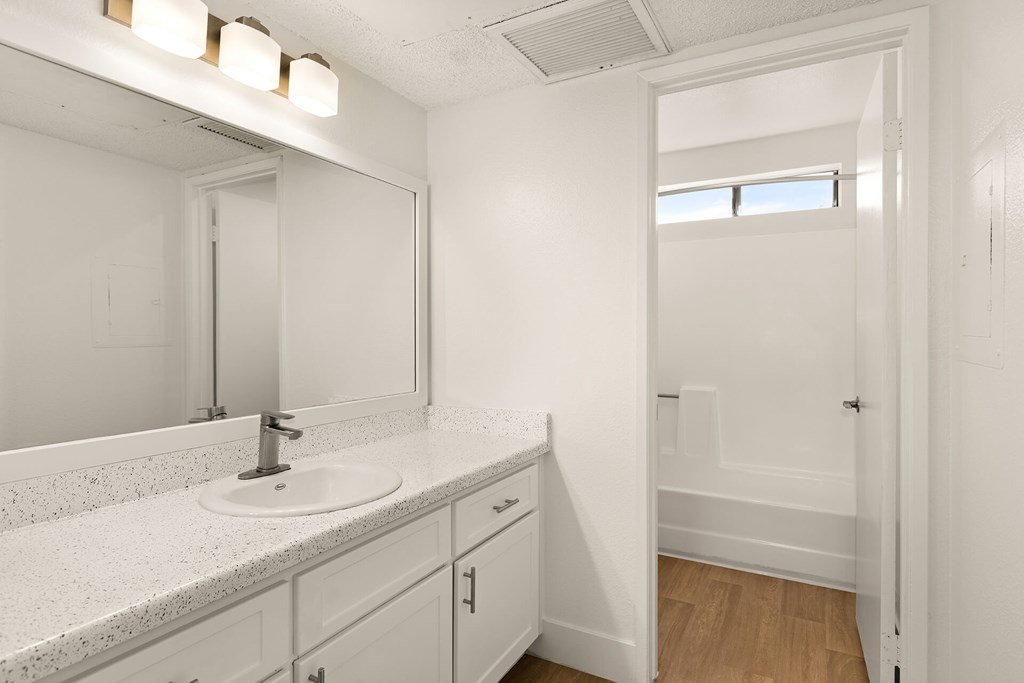 A white bathroom with a sink and mirror.