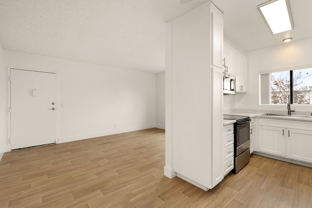 A kitchen with white cabinets and a wooden floor.