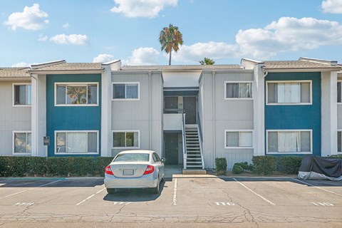 A car is parked in a parking lot in front of a building.