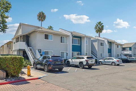A parking lot with cars and a building with palm trees in the background.