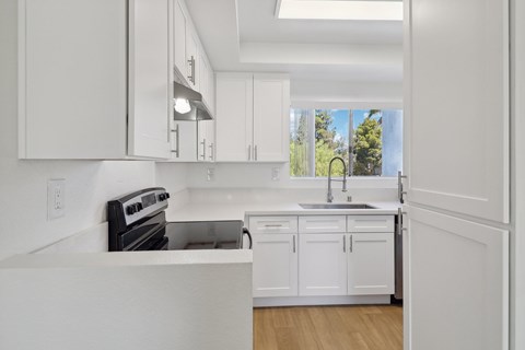 A modern kitchen with white cabinets and appliances.