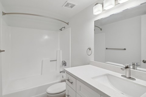 A white bathroom with a toilet, sink, and mirror.
