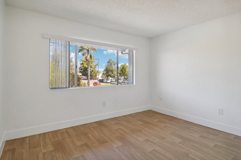 A room with a window showing a view of trees and a street.
