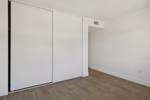 A room with a white wall and a white closet with a black frame.