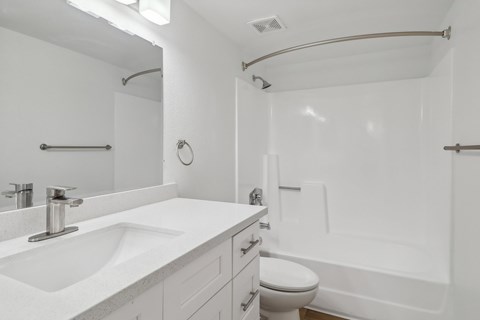 A white bathroom with a sink, toilet, and bathtub.