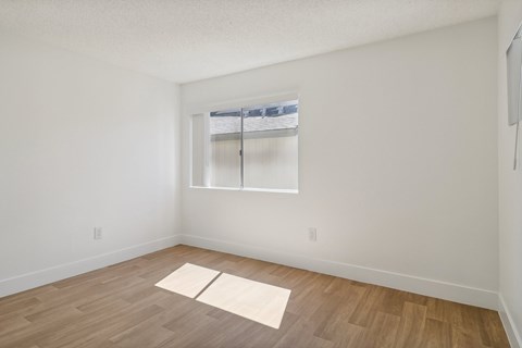 A room with a window and a wooden floor.