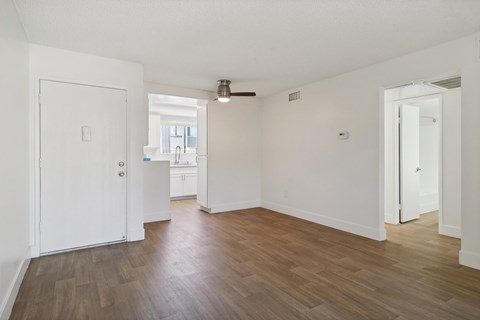 A room with white walls and wooden flooring with a door on the left and another door on the right.
