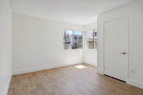 A room with a white door and a window with a view of a city.