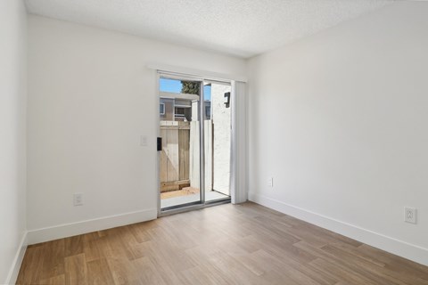 A room with a sliding glass door leading to a balcony.