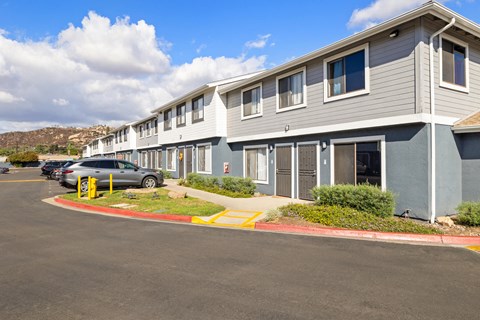 A row of houses with a car parked in front of the first one.