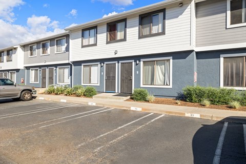 A parking lot in front of a building with grey and blue siding.