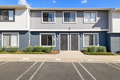 A row of townhouses with a parking lot in front.