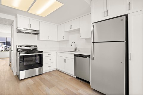 A modern kitchen with a refrigerator, oven, and sink.
