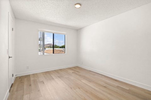 Empty room with wooden floor and a window showing an outdoor view.