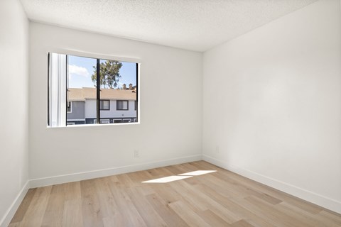A room with a window showing a view of a building outside.