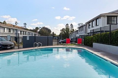 A swimming pool in a residential area with houses and trees in the background.