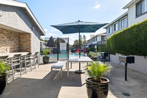 A patio with a table and chairs and a pool in the background.