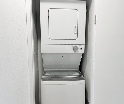 A white dishwasher is installed in a white wall.