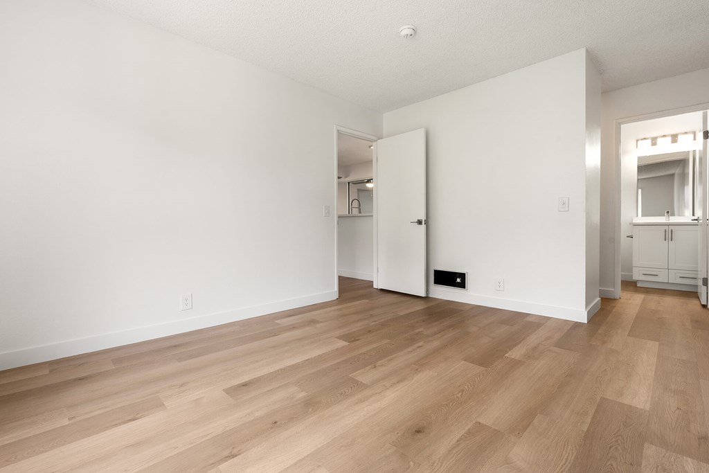 A room with wooden flooring and white walls.