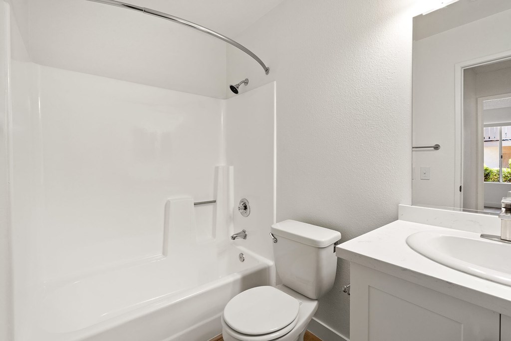 A white bathroom with a toilet, sink, and bathtub.