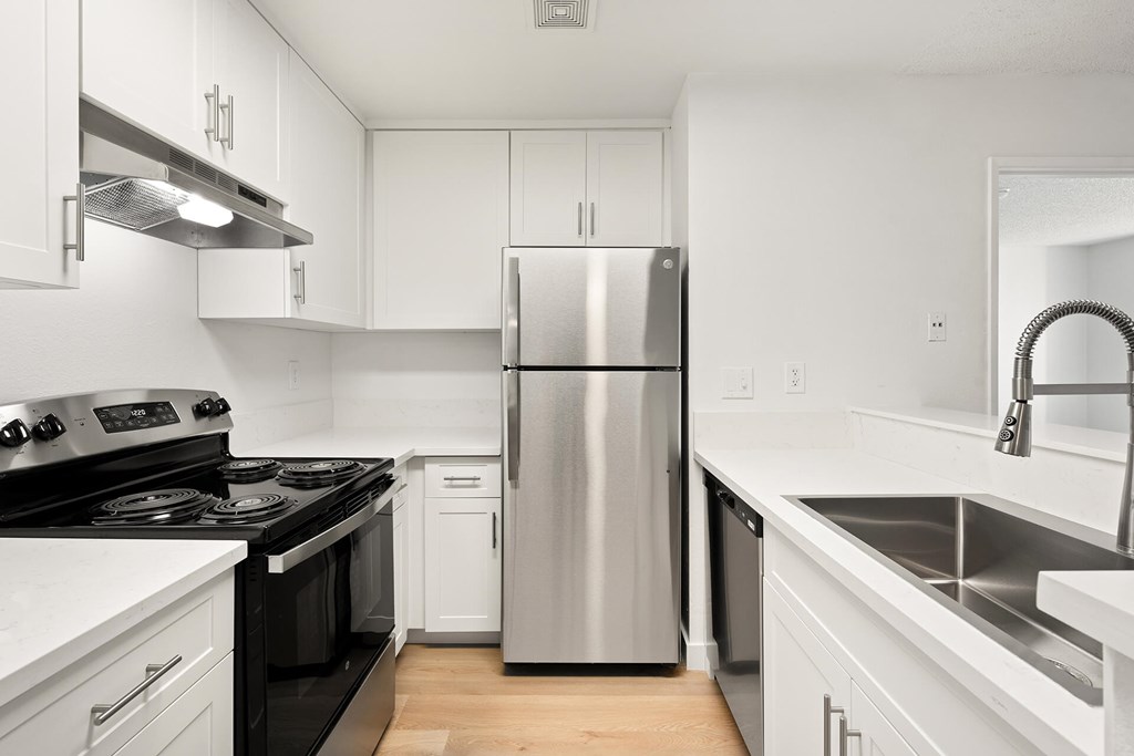 A modern kitchen with a stainless steel refrigerator and black countertops.